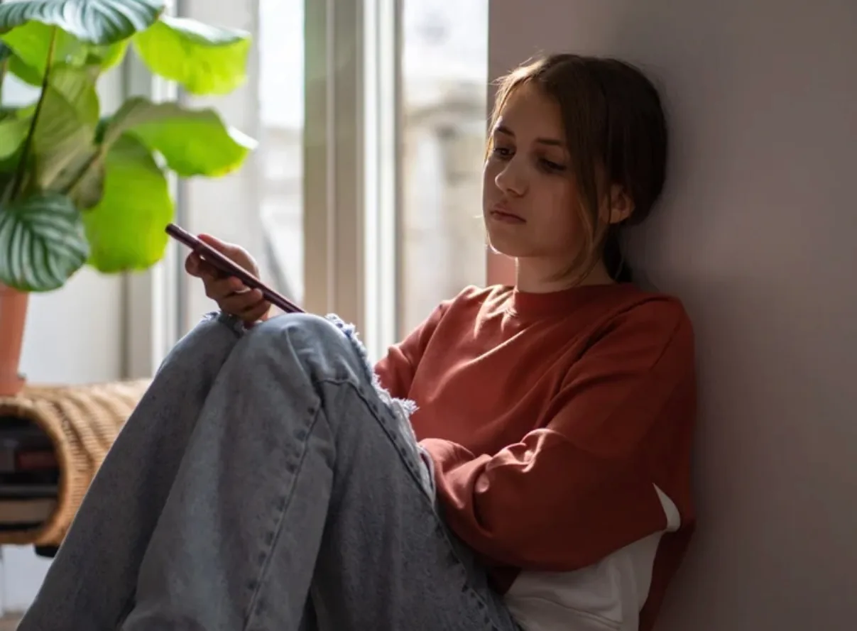 Persona pensativa mirando por la ventana con una taza tibia, diferenciando la tristeza de la depresión clínica